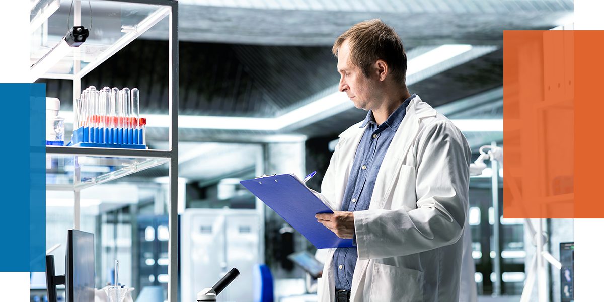 A lab worker holding a clipboard in a laboratory.