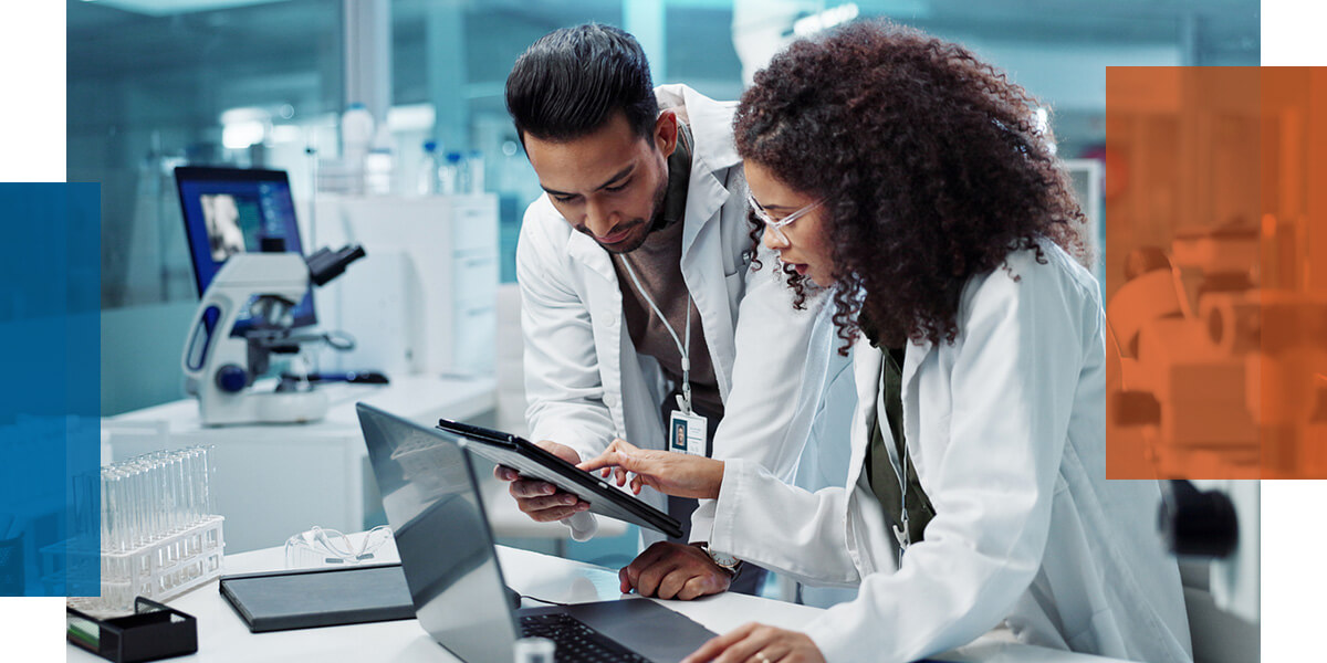 two scientists benchmarking a labs results on a tablet and laptop